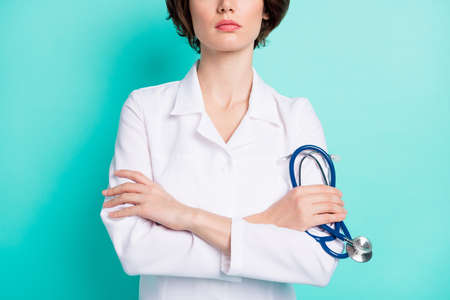 Cropped photo of young woman folded hands hold stethoscope doctor wear uniform isolated over teal color backgroundの写真素材