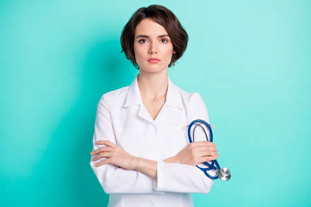 Photo of young woman serious crossed hands hold stethoscope therapist clinic illness isolated over teal color backgroundの写真素材