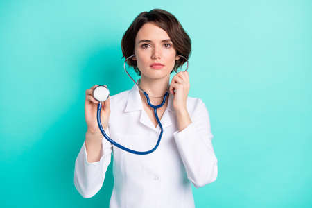 Photo of young woman serious hold stethoscope listen doctor hospital isolated over teal color backgroundの写真素材