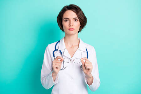 Photo portrait of serious female doctor wearing white uniform with stethoscope isolated vivid teal color backgroundの写真素材