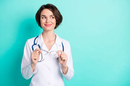 Photo portrait of cheerful female doctor wearing white uniform looking copyspace isolated bright teal color backgroundの写真素材