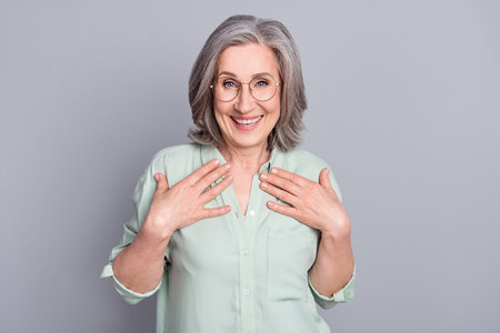 Photo of happy excited cheerful grandmother point herself unexpected victory isolated on grey color...