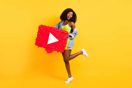 Full length body size view of attractive cheerful girl holding big video button dancing isolated over bright yellow color backgroundの写真素材