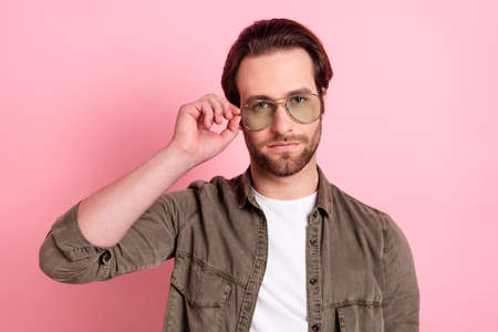Photo of young handsome man serious confident macho hand touch glasses isolated over pastel color backgroundの写真素材