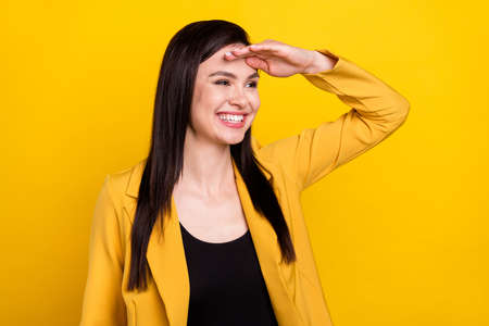 Photo of cute charming young woman wear formal jacket arm forehead looking empty space smiling isolated yellow color backgroundの写真素材