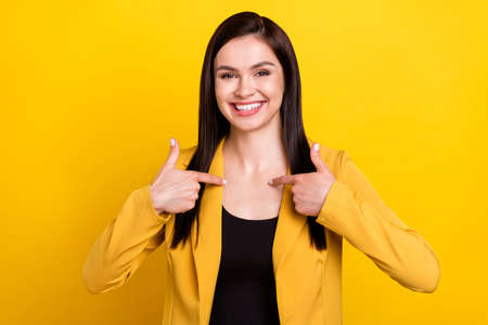 Photo of young cheerful woman happy positive smile point finger herself proud victory isolated over yellow color backgroundの写真素材