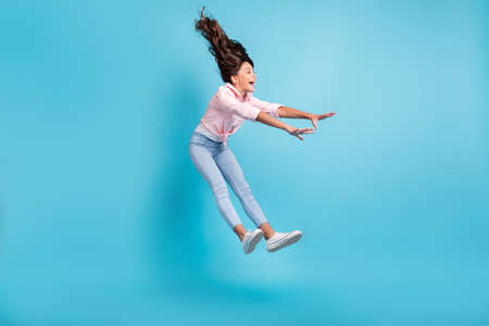 Full length photo of astonished carefree kid playing jumping falling open mouth isolated on blue color backgroundの写真素材