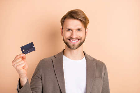 Photo of optimistic nice blond hair man show card wear grey jacket isolated on beige background
