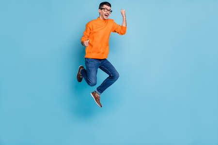 Full body profile portrait of astonished man open mouth fists up look empty space isolated on blue...