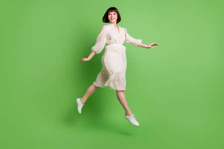 Full length body size photo woman wearing dotted dress jumping up running smiling isolated pastel...