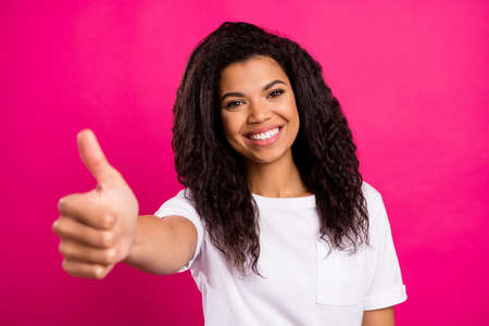 Photo of gorgeous brunette curly young lady show thumb up wear white t-shirt isolated on vivid pink color backgroundの写真素材