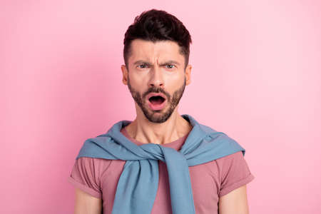 Photo of unhappy shocked angry young man bad mood news negative isolated on pastel pink color backgroundの写真素材