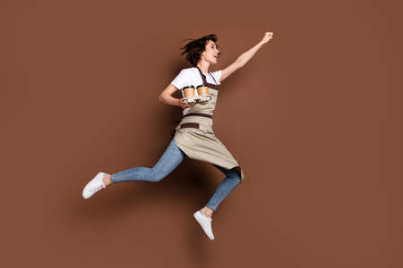 Full length body size view of beautiful cheerful girl bringing coffee jumping striving success isolated over brown color backgroundの写真素材