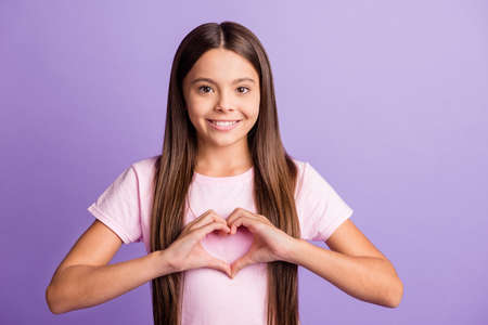 Photo of young girl happy positive smile show fingers heart sign feelings valentine day isolated over violet color backgroundの写真素材