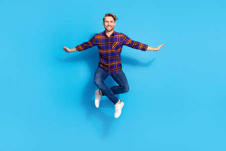 Full length body size view of attractive cheerful funny guy jumping posing isolated over vivid blue...