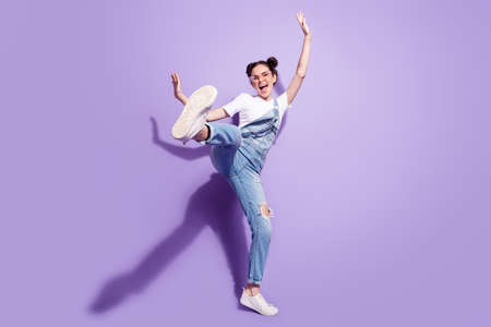 Photo of funky cute young lady wear jeans overall spectacles dancing walking isolated violet color...