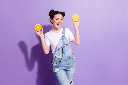 Portrait of excited positive girl arms hold demonstrating half orange toothy smile isolated on purple color backgroundの写真素材