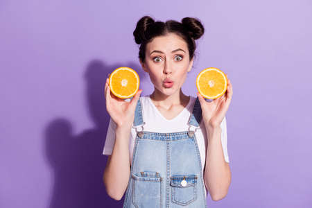 Photo of young attractive girl amazed excited surprised hold fruit orange food isolated over violet color backgroundの写真素材