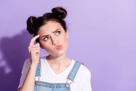 Photo of focused person finger on temple look interested empty space isolated on violet color backgroundの写真素材