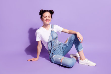 Full length portrait of adorable satisfied young girl sit toothy smile look camera isolated on purple color backgroundの写真素材