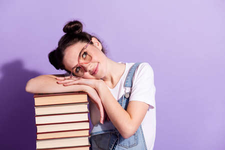 Photo of young girl happy positive smile dream dreamy look empty space books isolated over violet color backgroundの写真素材