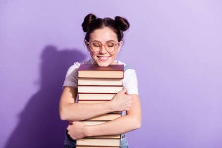Photo of young excited girl happy positive smile hug books student isolated over violet color backgroundの写真素材