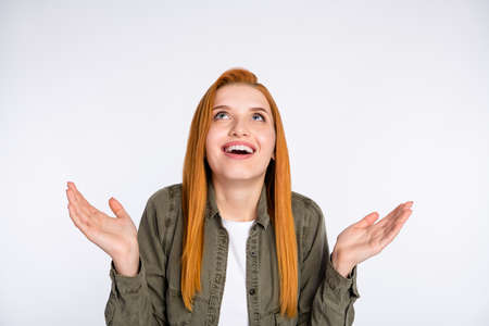 Portrait of attractive cheerful red haired girl expecting good news looking up isolated over white...