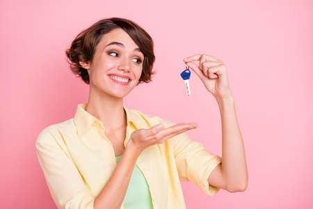 Photo of shiny excited young woman wear yellow shirt holding news house keys isolated pink color backgroundの写真素材