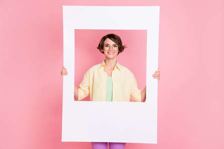 Photo of optimistic brunette lady hold frame wear shirt isolated on pastel pink color backgroundの写真素材