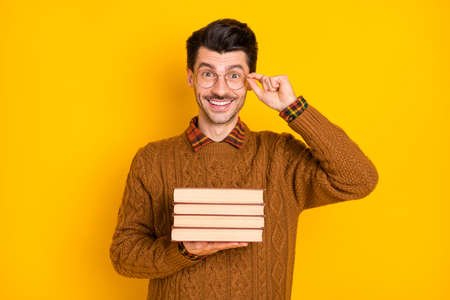 Photo of smart charming man hold pile books materials test prepare isolated on yellow color backgroundの写真素材