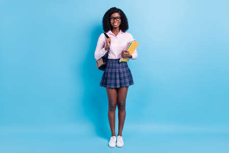 Full body photo of young student girl happy smile hold copybooks lessons education isolated over blue color backgroundの写真素材