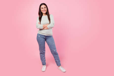 Full length photo of attractive young happy woman look empty space hold arm folded isolated on pink color backgroundの写真素材