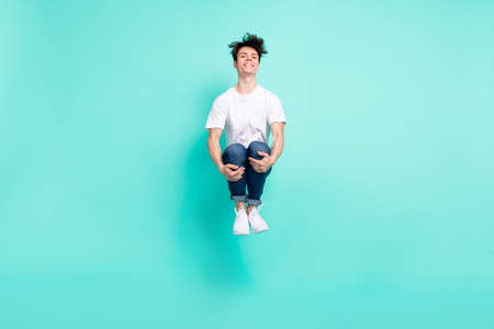 Full body photo of funny brunet hairdo teen guy jump wear t-shirt jeans isolated on teal background