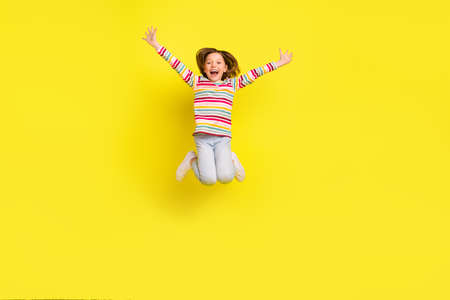 Full body photo of impressed short hairdo little girl jump wear shirt trousers sneakers isolated on yellow color backgroundの写真素材