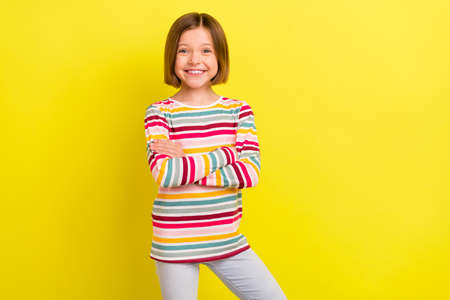 Photo of charming young happy small girl hold hands crossed smile confident isolated on yellow color...