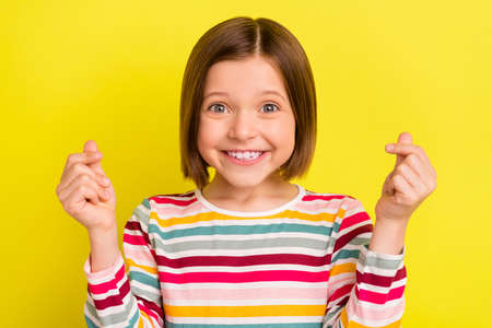 Photo of nice happy lovely little girl make fingers hearts crossed smile isolated on bright yellow...