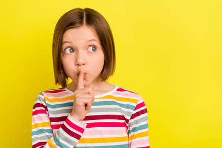 Photo portrait little girl in with bob hairstyle gossiping keeping secret looking copyspace isolated vivid yellow color backgroundの写真素材