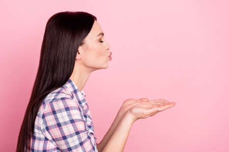 Profile side view portrait of attractive dreamy girl sending air kiss copy empty space isolated over pink pastel color backgroundの写真素材