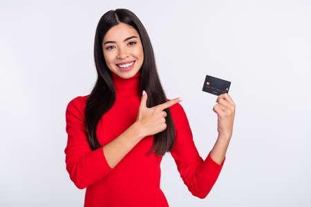 Photo of young smiling charming positive asian girl advertise credit card recommendation isolated on...