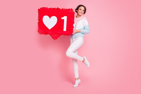 Full size portrait of pretty cheerful girl hands hold collage like subscribe isolated on pink color backgroundの写真素材