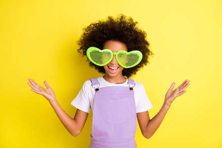 Photo of little girl open hands beaming smile wear retro sunglass purple overall isolated yellow...