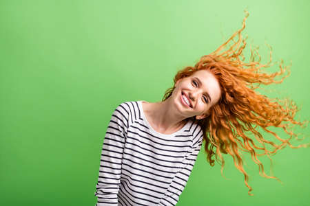 Photo of funky charming young lady dressed striped clothes smiling wind blowing isolated green color backgroundの写真素材