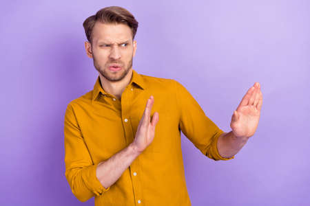 Portrait of attractive trendy guy showing aside stop sign decline protest protection isolated over...