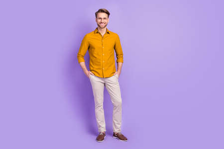 Photo of confident sweet young guy wear casual clothes glasses arms pockets smiling isolated purple color backgroundの写真素材