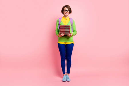 Full length photo of cute young lady dressed yellow shirt glasses backpack holding book stack...