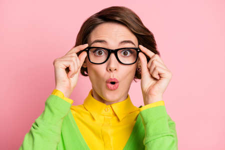 Photo of amazed shocked schoolgirl hold look wear glasses unexpected news isolated on pastel pink...