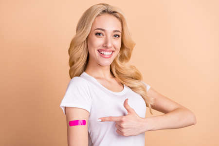 Photo portrait woman smiling showing vaccination patch isolated pastel beige color backgroundの写真素材