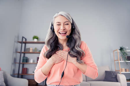 Photo of aged woman happy positive smile hands on chest humor joke laugh talk microphone listen conversation homeの写真素材