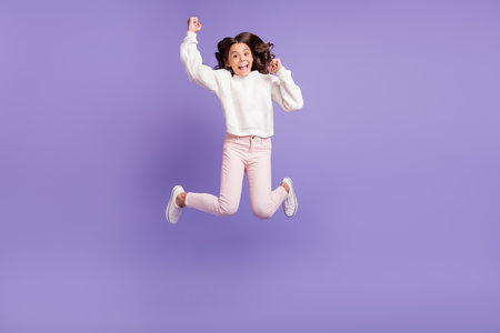 Full body photo of young excited girl jump happy smile celebrate win victory lucky fists hands isolated over violet color backgroundの写真素材