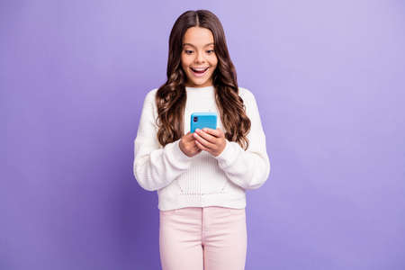 Photo of young happy excited shocked amazed girl wear pink pants hold smartphone isolated on violet...